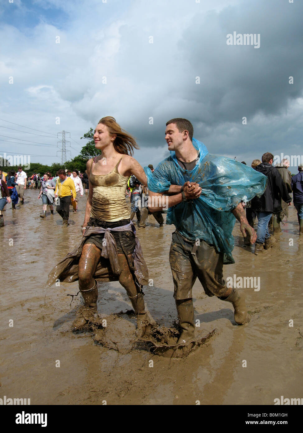 Fêtards s'exécuter dans la boue à Glastonbury Festival 2007 Banque D'Images