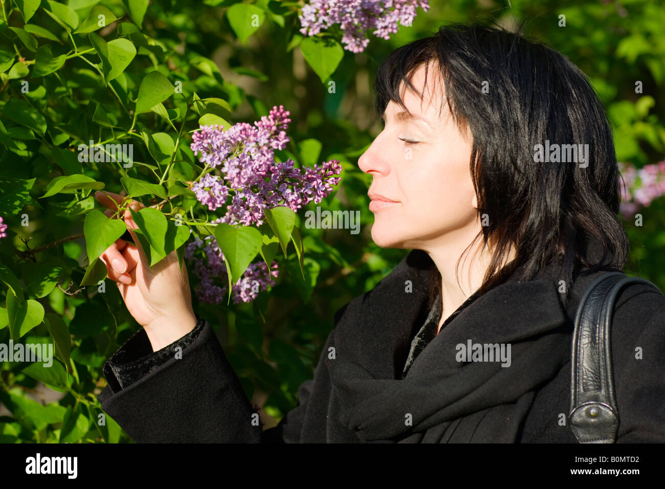 Middle aged woman smelling Flowers in the park garden Banque D'Images