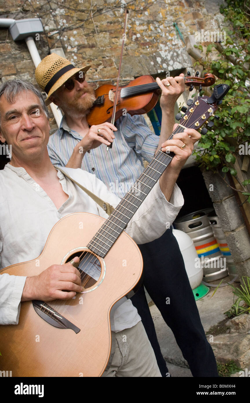 Deux musiciens folk jouant de la guitare acoustique et de la musique de violon violon à l'extérieur, mariage Druidstone, Pembrokeshire Wales UK Hotel Banque D'Images