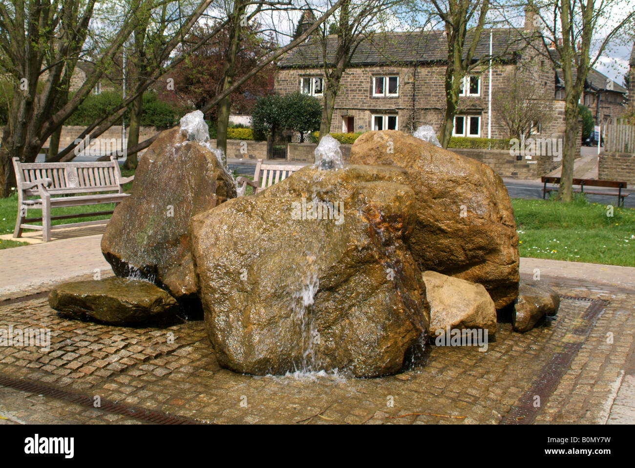 Une fontaine d'eau dans un morceau de sculpture moderne dans un parc de la rue principale de Burley Wharfedale Banque D'Images