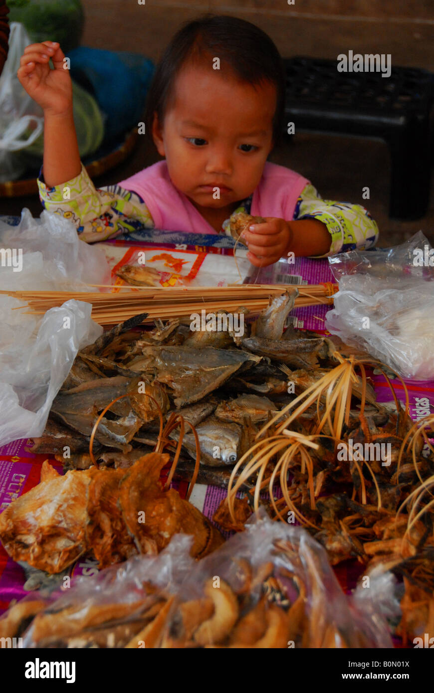 À gauche de l'enfant à jouer avec les poissons tandis que maman vend du poisson au marché intérieur Banque D'Images