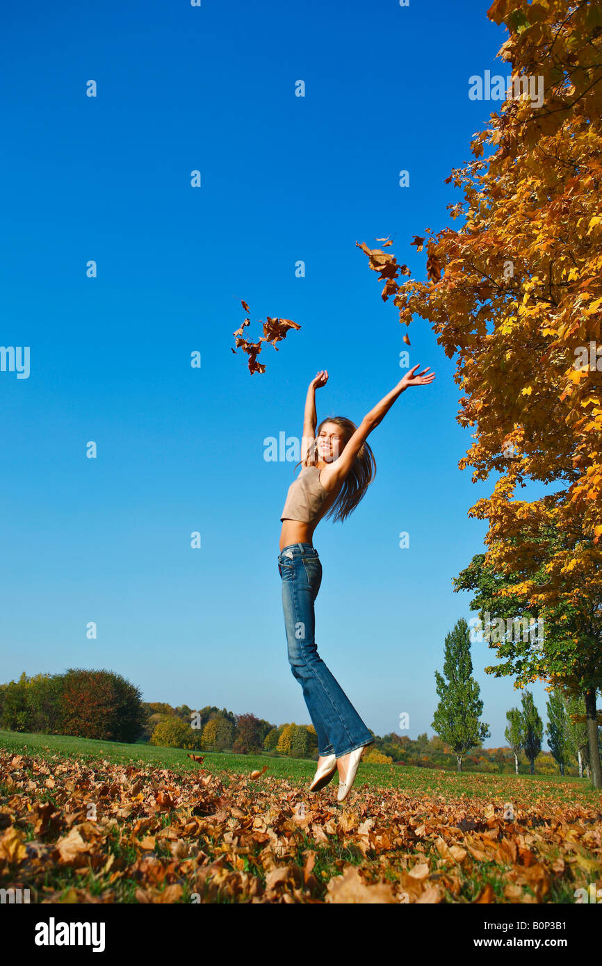 De l'automne. La jeune fille dans les sauts du parc, il est heureux. Banque D'Images