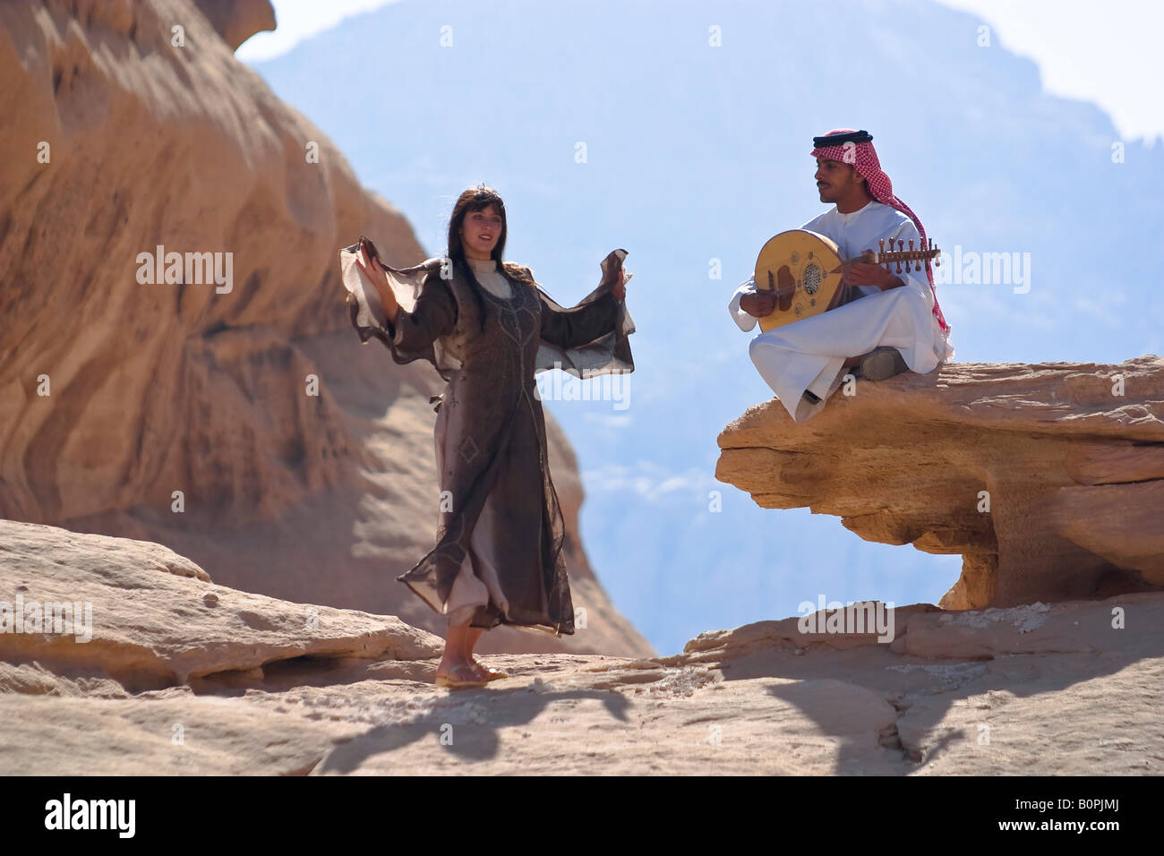 La Jordanie. Désert du Wadi Ram. La jeune femme dans les vêtements nationaux des danses. Jeune homme joue sur un instrument de musique. Banque D'Images