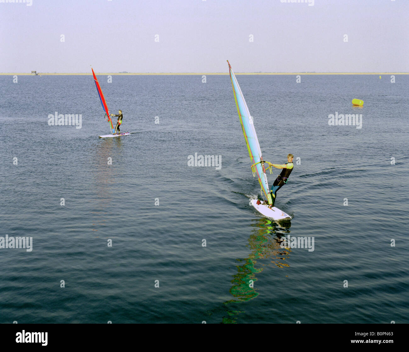 Deux jeunes hommes des planches à pratiquer leur sport sur le réservoir en Covenham Angleterre Lincolnshire Banque D'Images