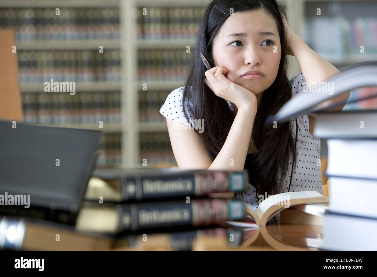 Jeune femme frustrée studying in library Banque D'Images