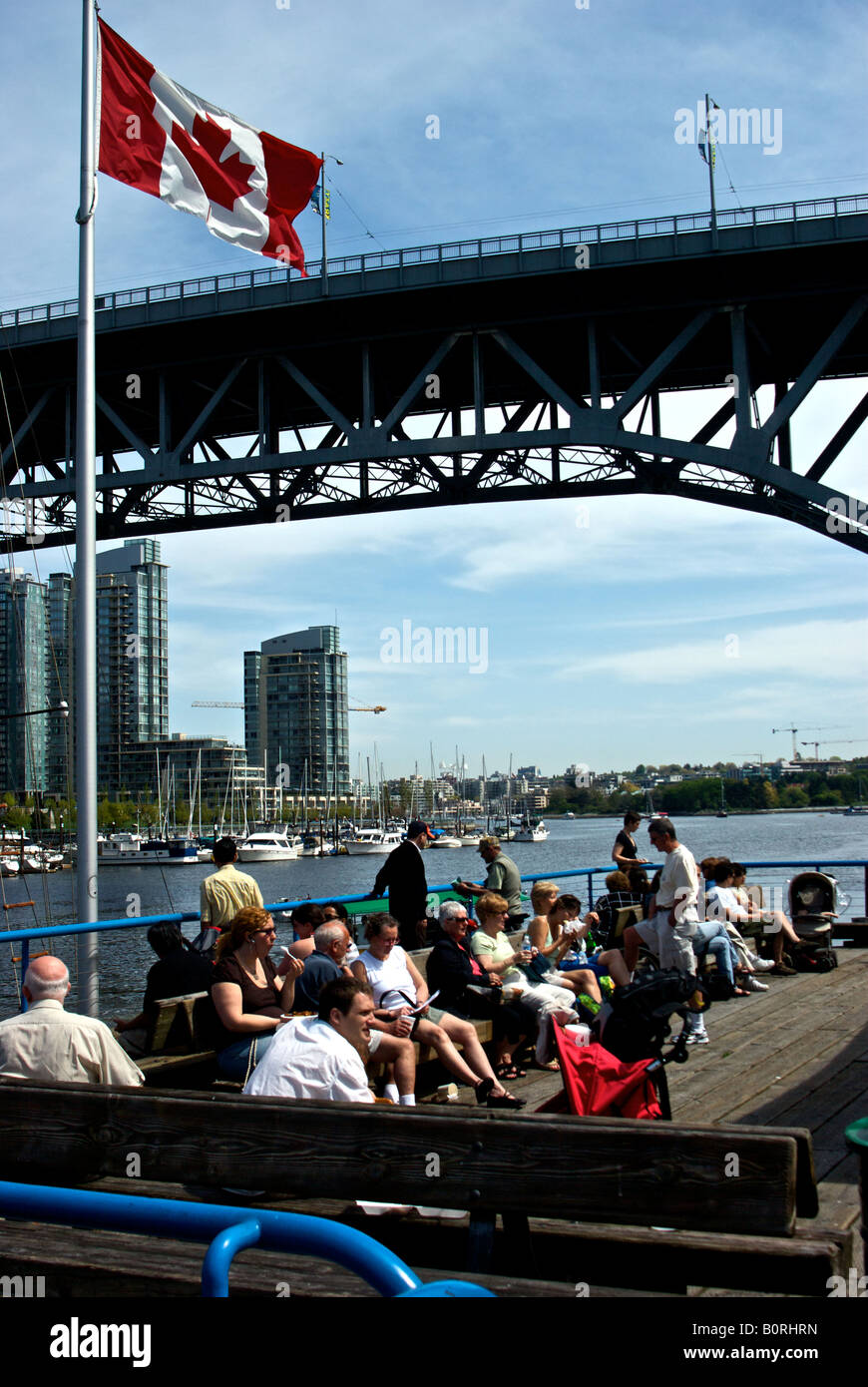 Les Vancouvérois et les touristes profitant d'une chaude journée ensoleillée sous le sur le grand quai de False Creek waterfront. Banque D'Images