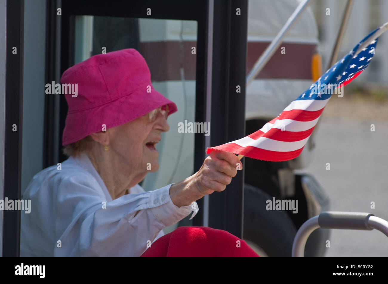 Personnes âgées Senior citizen woman in pink hat vagues USA flag, de marcheurs dans petite ville défilé patriotique. Banque D'Images