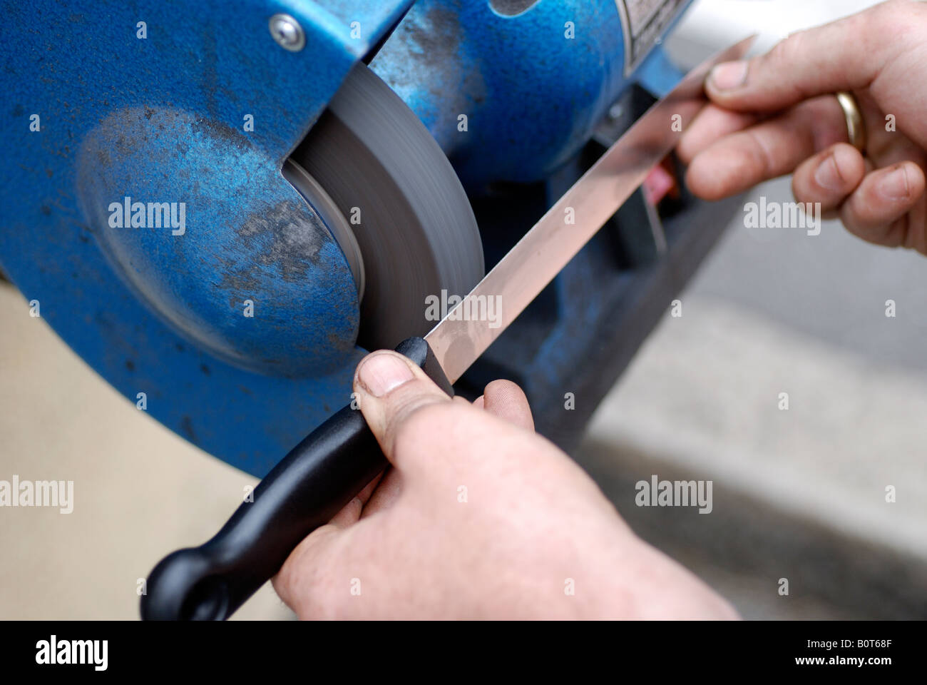 MAN SHOWING couteau de cuisine étant avivée par machine Banque D'Images