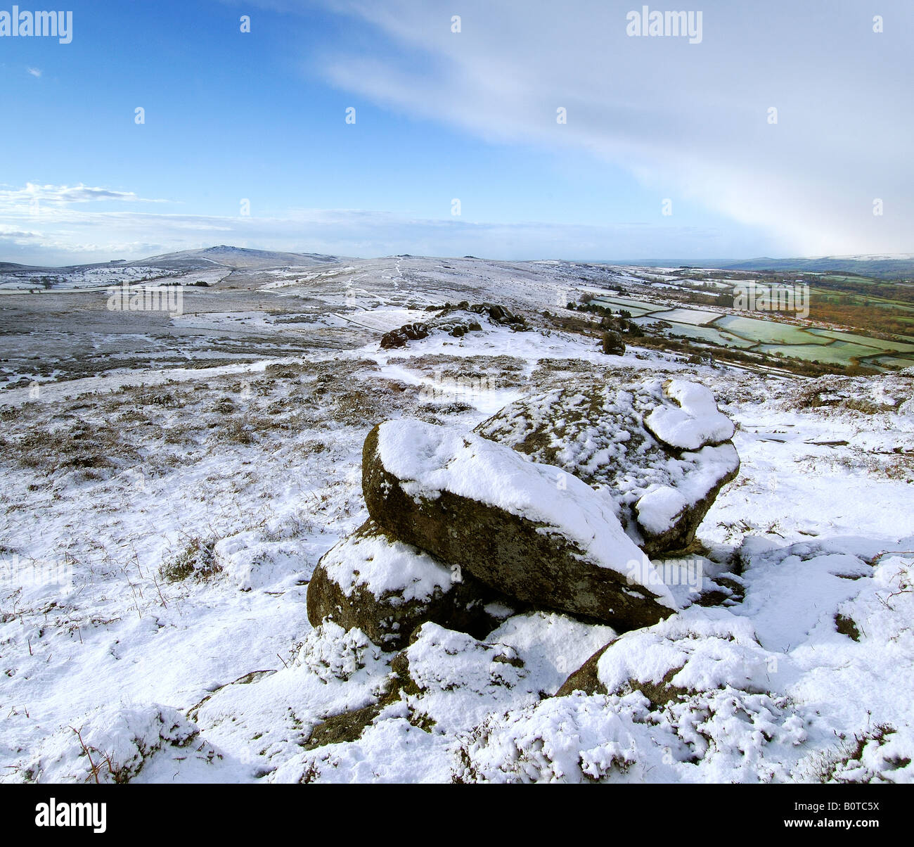 Le poids de la neige près de Chinkwell Tor sur le parc national du Dartmoor avec deux rochers de granit à l'avant-plan et widecombe vallée au-delà Banque D'Images