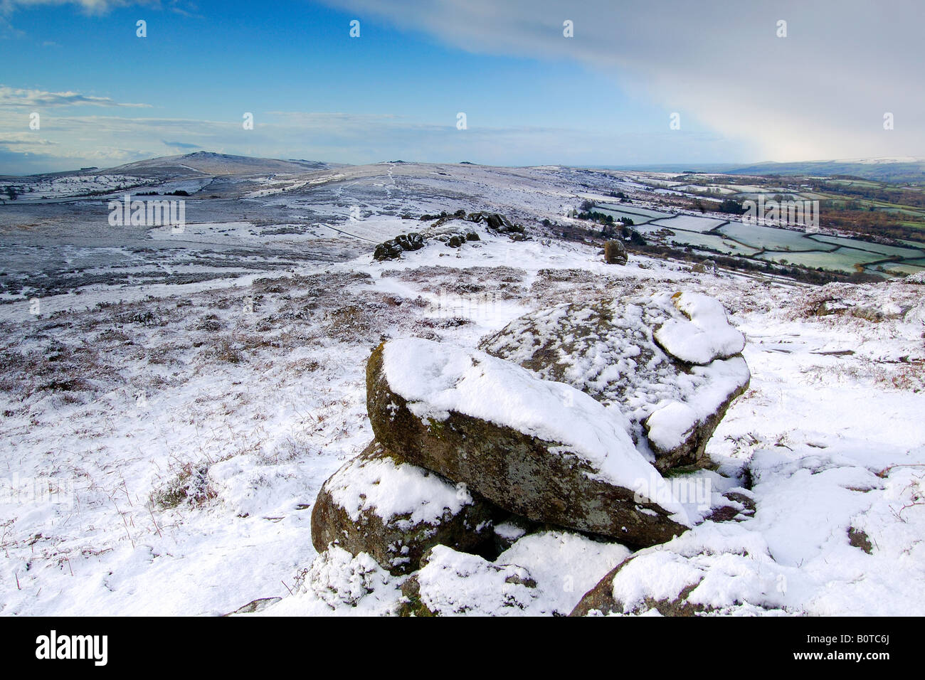 Le poids de la neige près de Chinkwell Tor sur le parc national du Dartmoor avec deux rochers de granit à l'avant-plan et widecombe vallée au-delà Banque D'Images