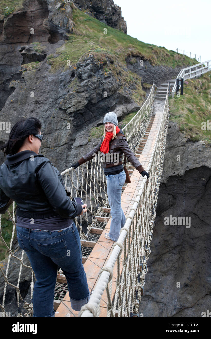 Deux femmes touristes posant sur le carrick a rede Rope Bridge sur le comté d'Antrim Coast Irlande du Nord Banque D'Images