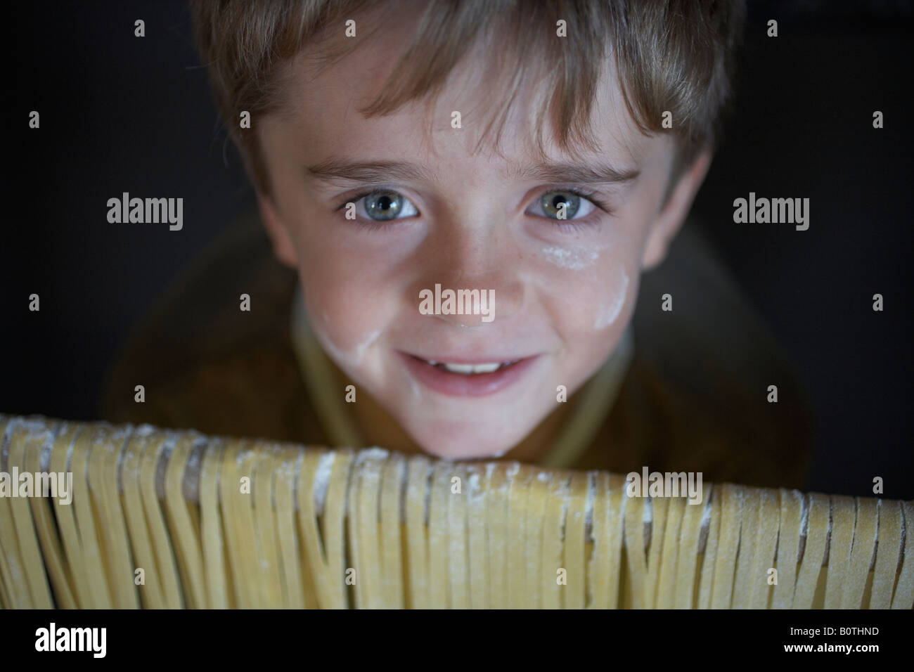 Garçon enfant à la rampe au drapé de pâtes fraîchement préparées Banque D'Images