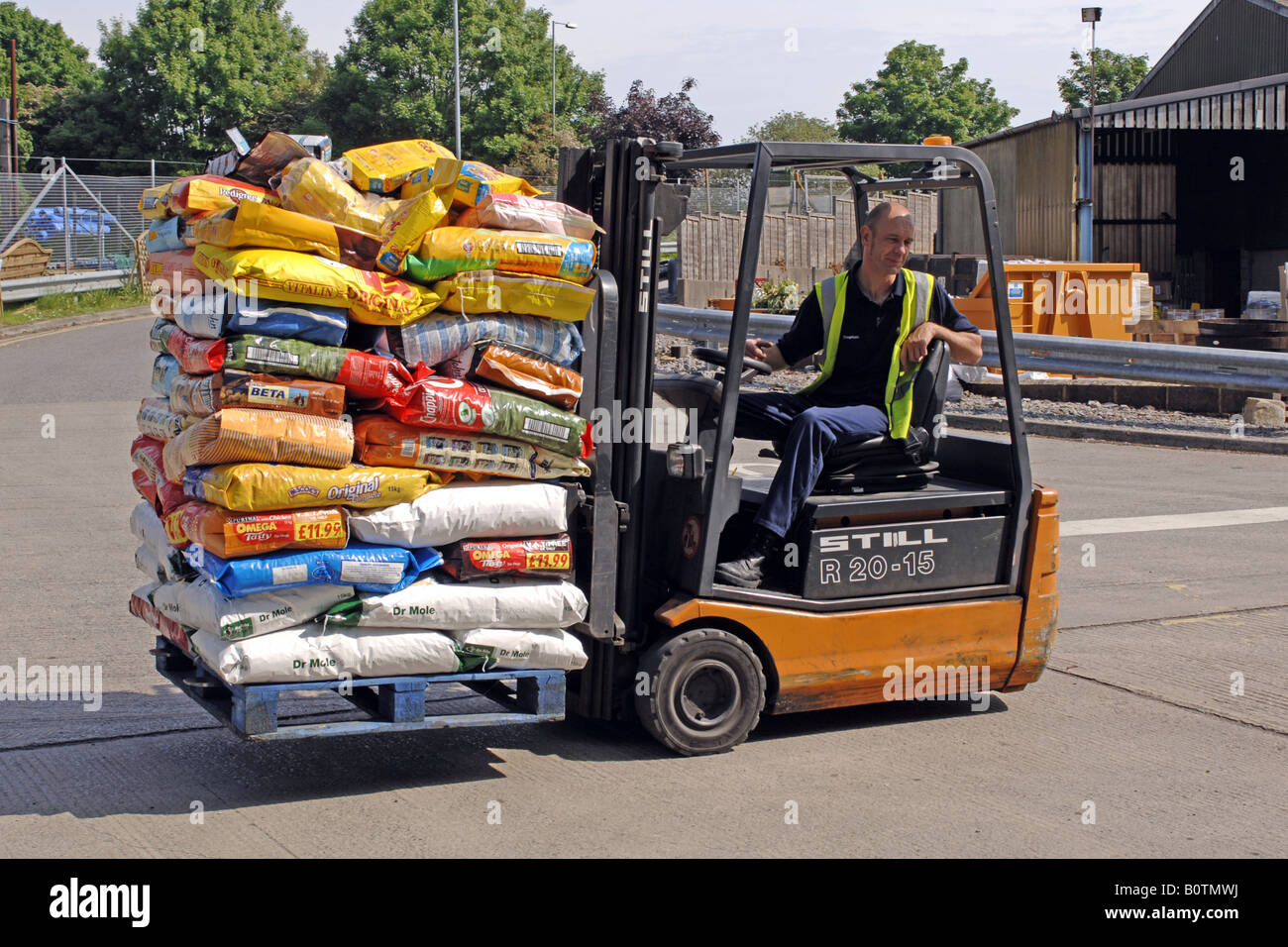 Un homme à l'aide d'un chariot élévateur pour déplacer des sacs de compost jardinage à un des approvisionnements de jardin Banque D'Images