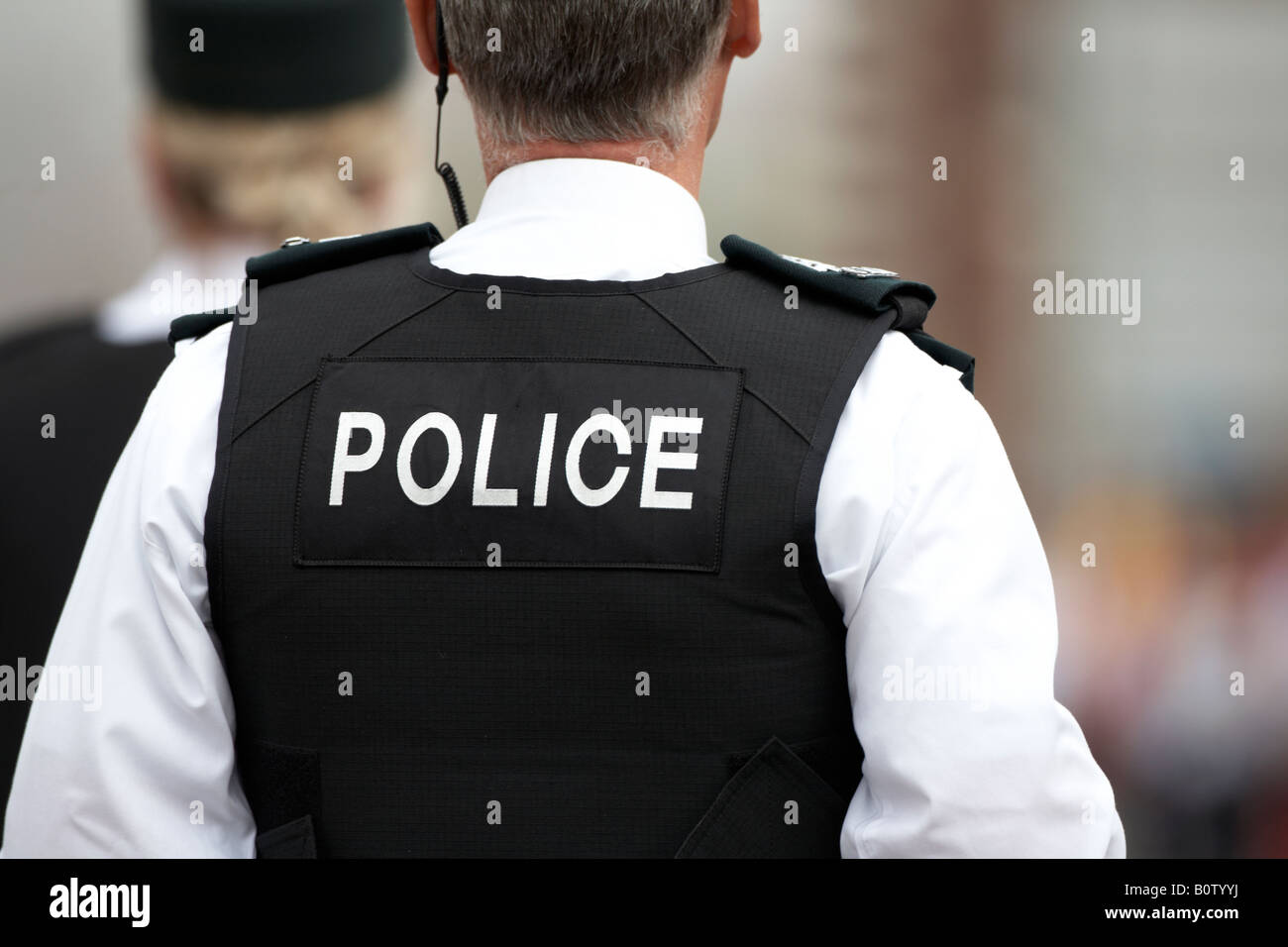 Service de police PSNI mâle d'Irlande le sergent en patrouille avec collègue portant des gilets stab et radio écouteur Banque D'Images