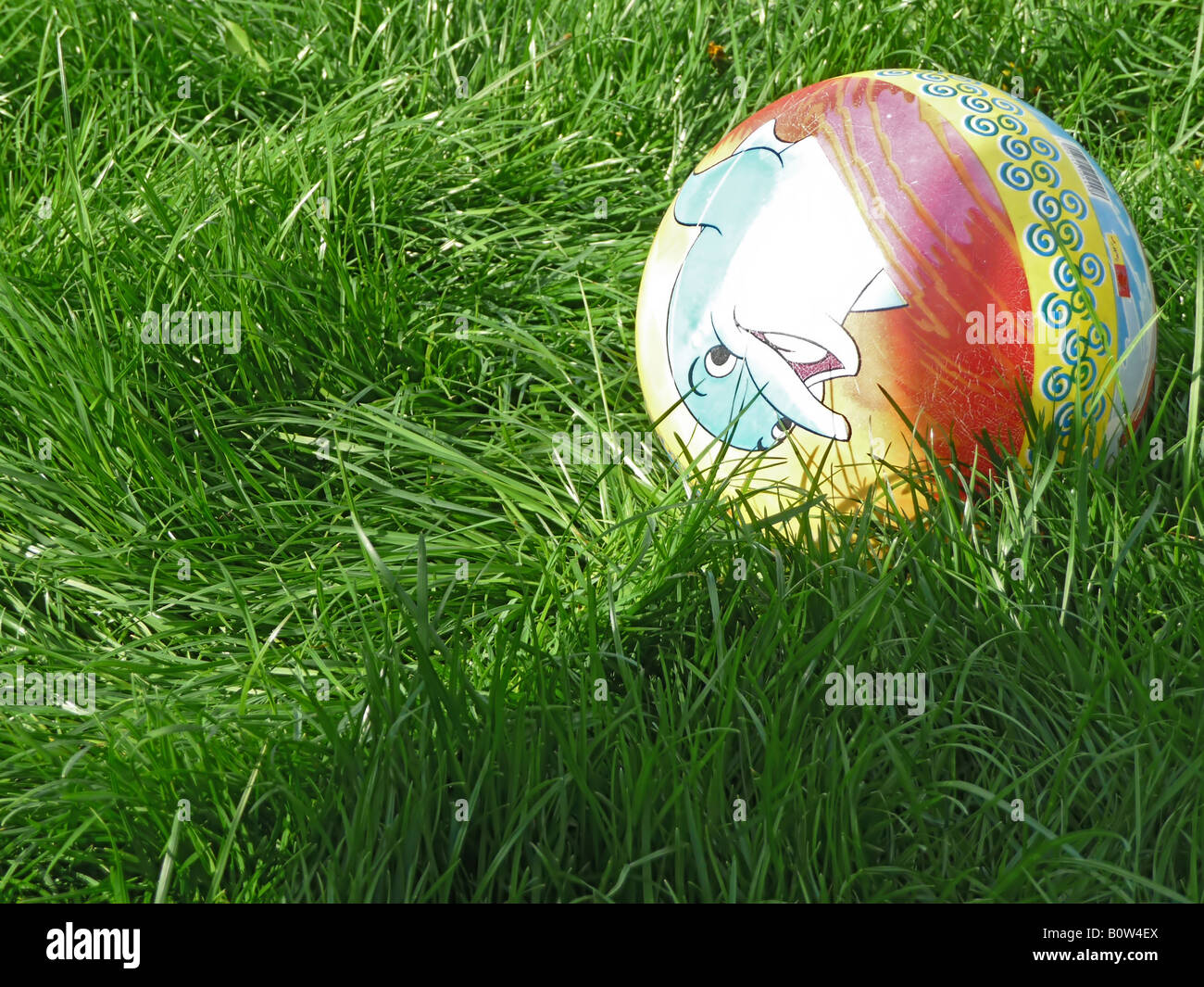 Une balle jouet pour enfants est de jeter dans l'herbe verte sous le soleil d'après-midi de printemps Banque D'Images