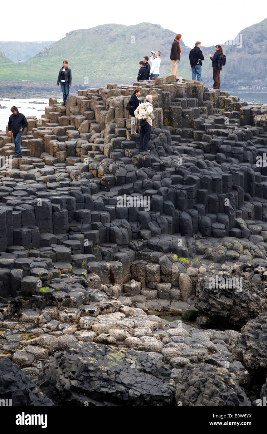 Les touristes se promener autour de l'hexagonal de basalte rouge rock formations à la Chaussée des Géants le comté d'Antrim en Irlande du Nord uk Banque D'Images