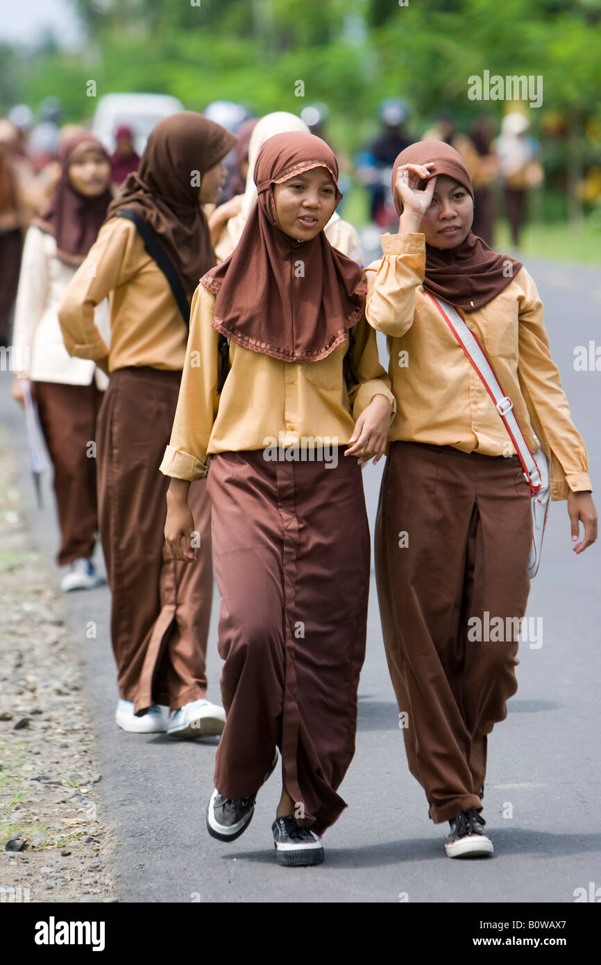 Les filles musulmanes, les écoliers portant leur uniforme de marcher le long d'une rue après l'école près de Mataram, Lombok, le petit soleil Banque D'Images