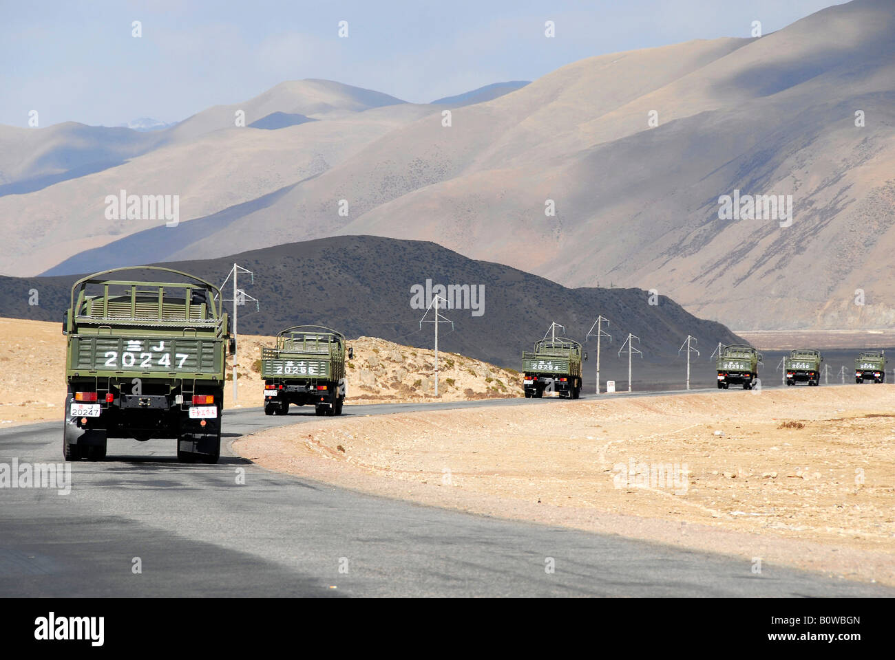 La conduite d'un convoi de camions militaires chinois sur une route pavée au Tibet, en Asie Banque D'Images