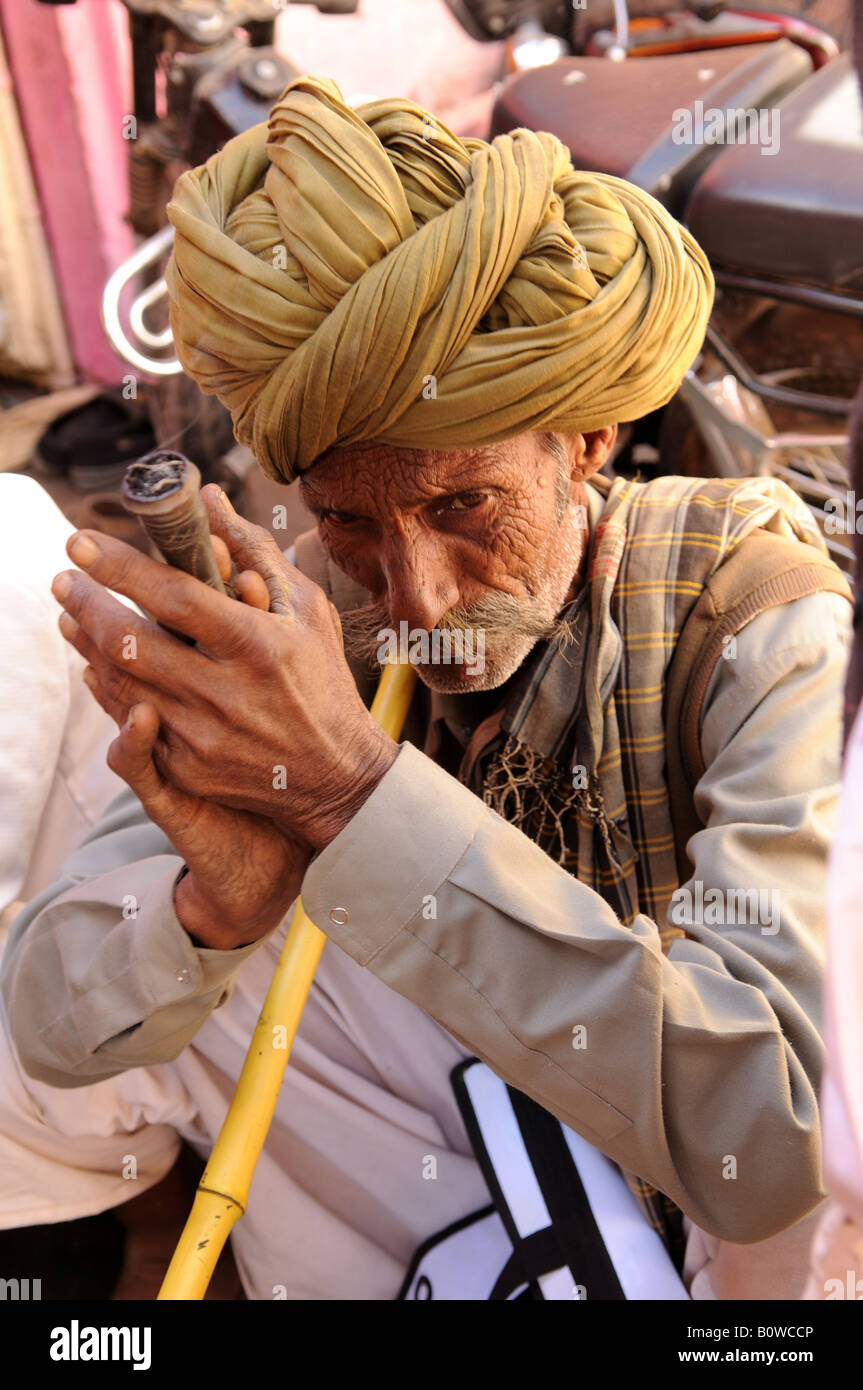 Un homme fume un Rajasthani traditionnelle pipe Chillum en Inde Banque D'Images