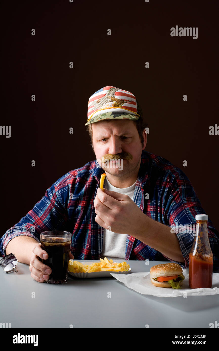 Les stéréotypes American man holding a french fry et regarder il Banque D'Images