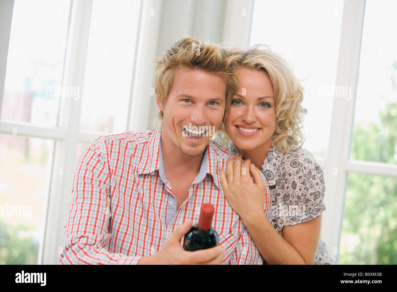 Young couple holding wine bottle, smiling, portrait Banque D'Images