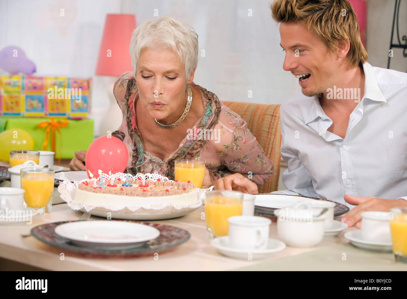 Woman blowing bougie sur torte, portrait Banque D'Images