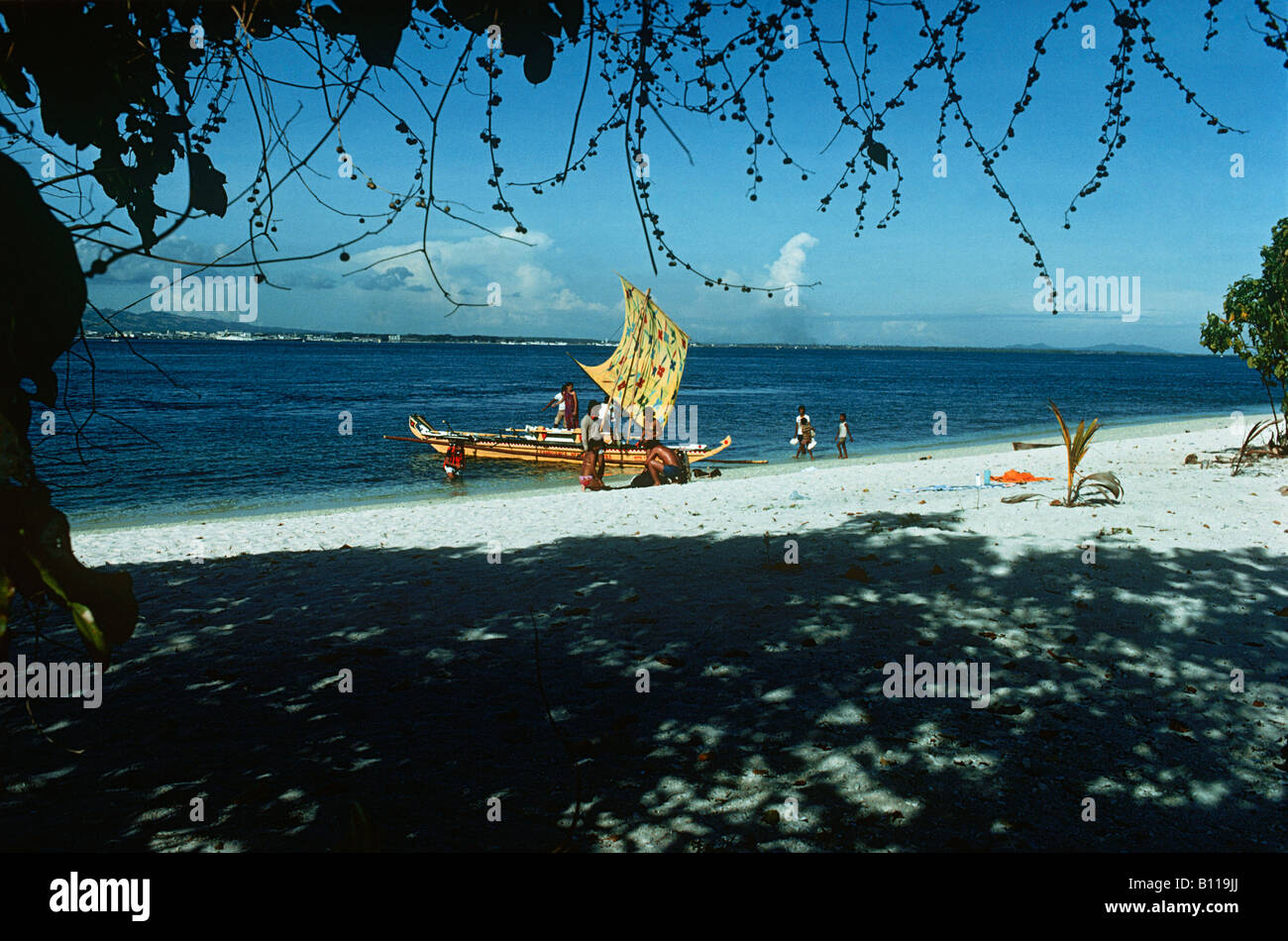 Les Philippines. Un bateau avec un jaune lumineux Vinta (voile) et un groupe de plongeurs met les voiles d'une plage sur l'île Santa Cruz. Banque D'Images