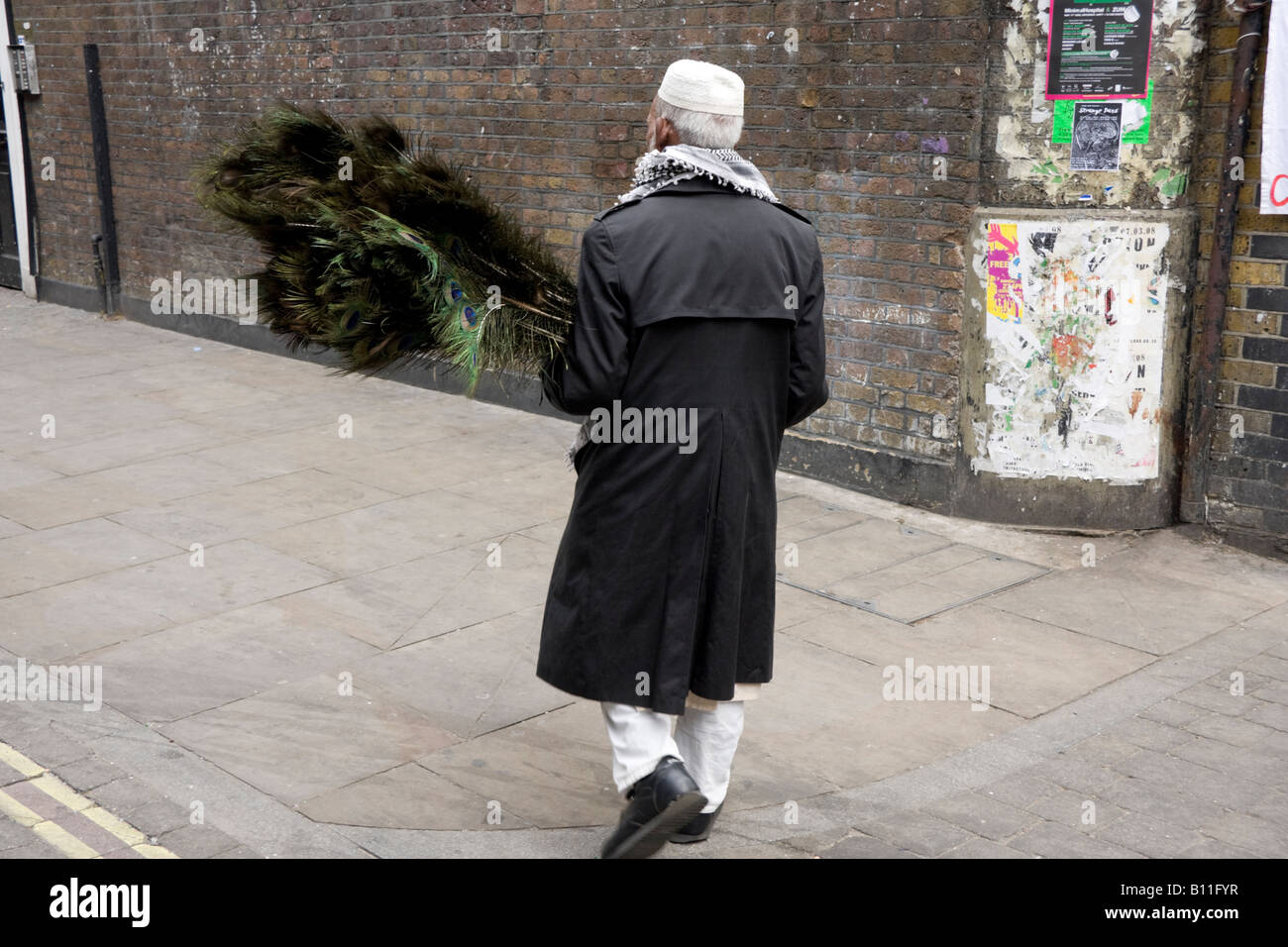 Personnes âgées l'homme du Bangladesh avec des plumes de paon dans Brick Lane London England Banque D'Images