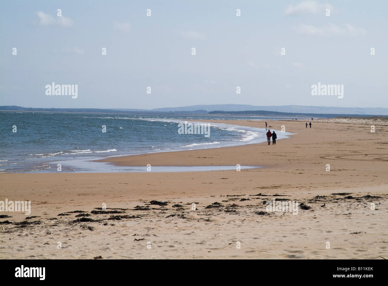dh Mer du Nord côte bord de mer DORNOCH FIRTH SUTHERLAND ÉCOSSE couple marchant sur la plage de sable personnes sable rivage plages écossaises marche Banque D'Images