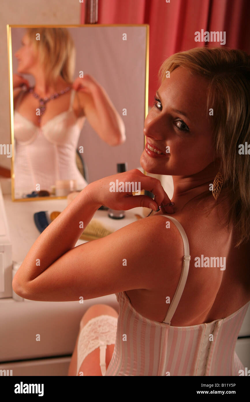 Young woman in front of mirror essayant sur un collier et à à l'épaule. Banque D'Images