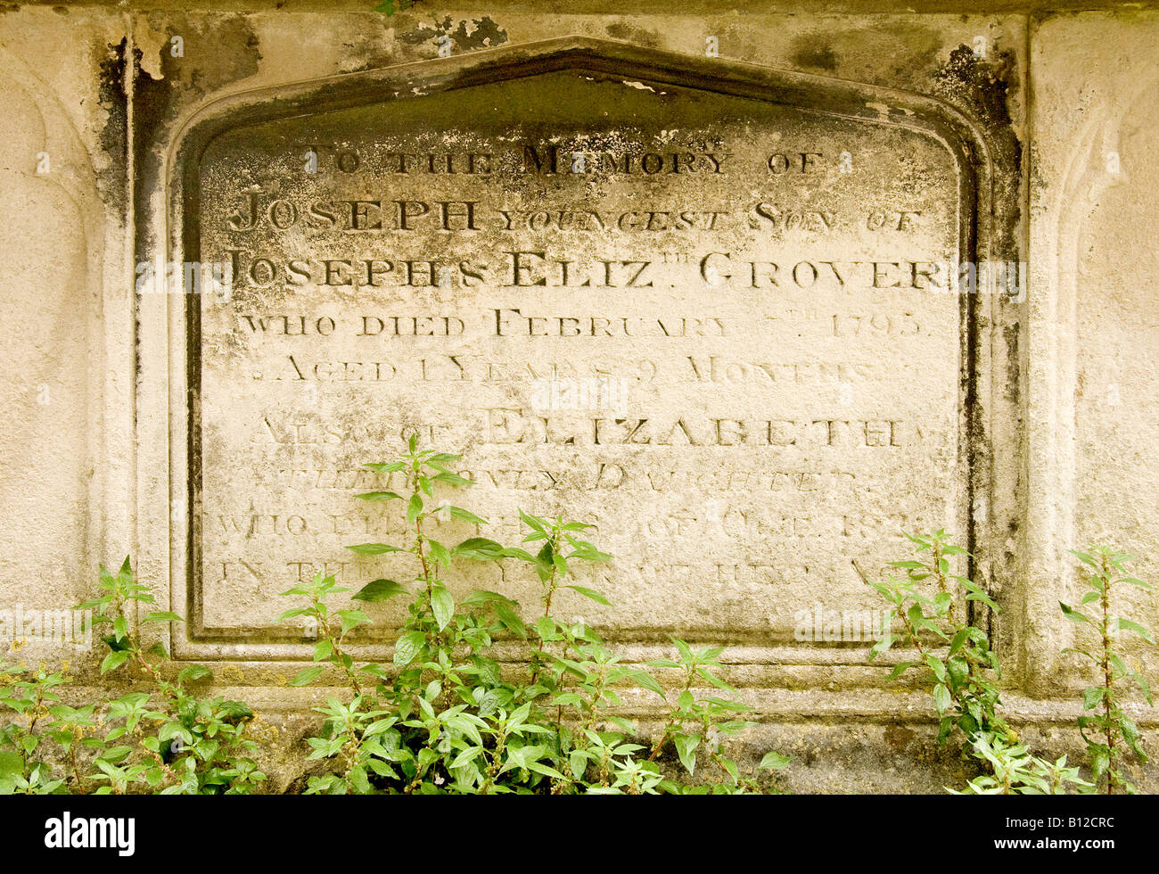 Pierre géorgienne tombe pierre tombale envahie par les mauvaises herbes dans un cimetière de l'église dans l'East Sussex Lewes Banque D'Images