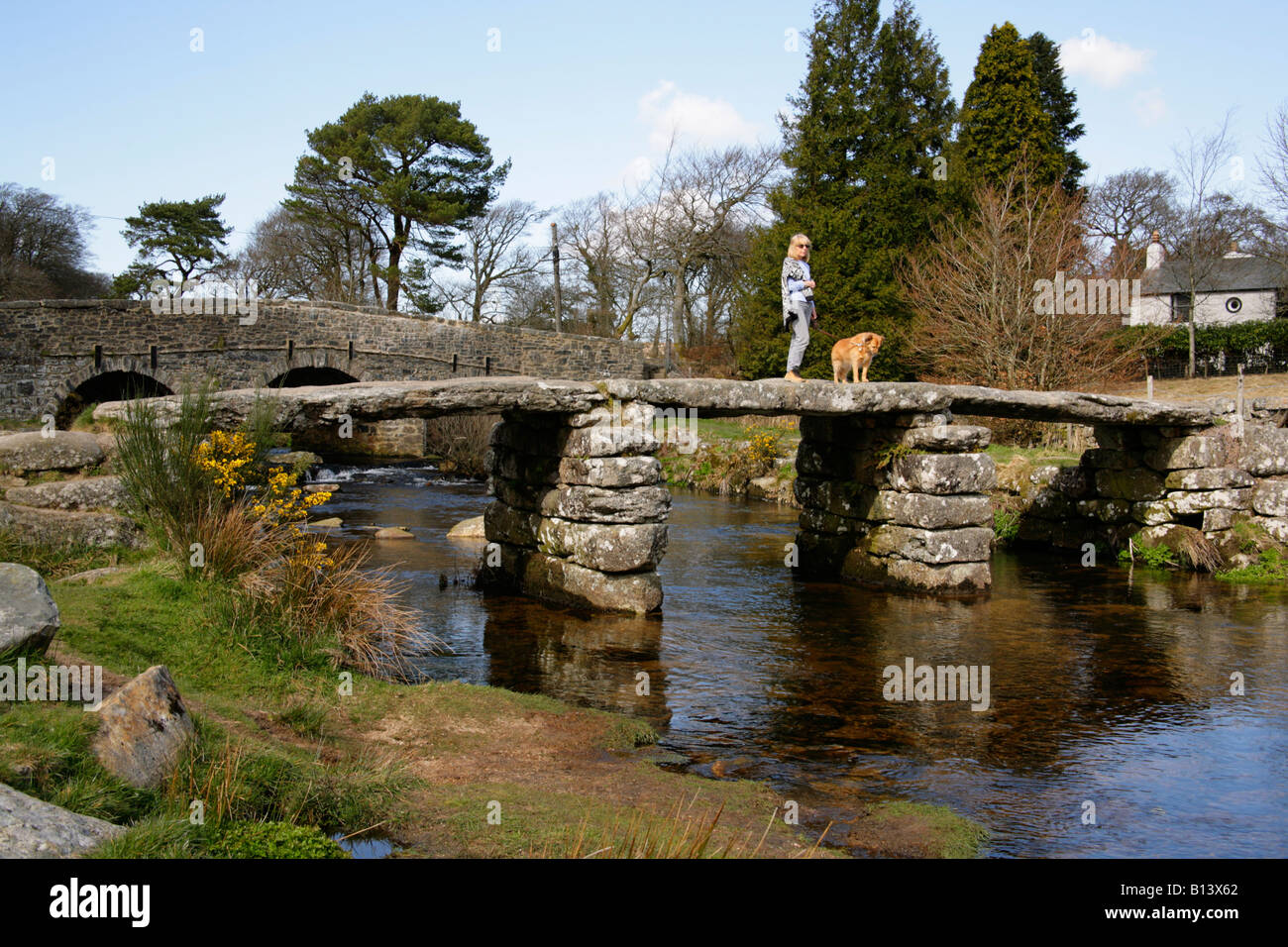 Figure féminine avec chien en granit antique clapper bridge à Postbridge, Dartmoor, dans le Devon. Banque D'Images