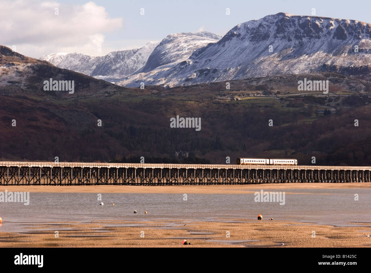 Un train traversant l'estuaire de Mawddach en direction de Barmouth. Cadair Idris enneigé, Penygader, en arrière-plan. Banque D'Images