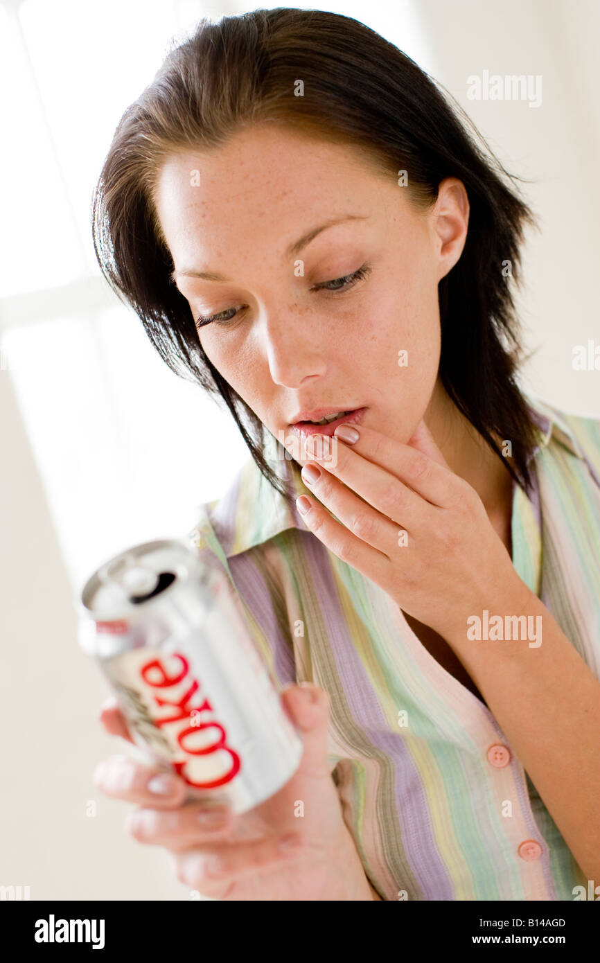 Girl reading contenu à l'arrière du cola tin Banque D'Images