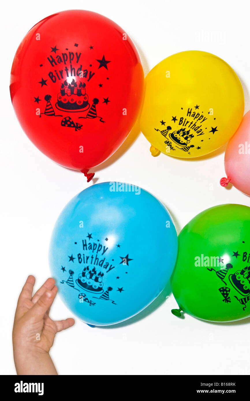 Petit garçon essayant d'atteindre des ballons d'anniversaire Banque D'Images