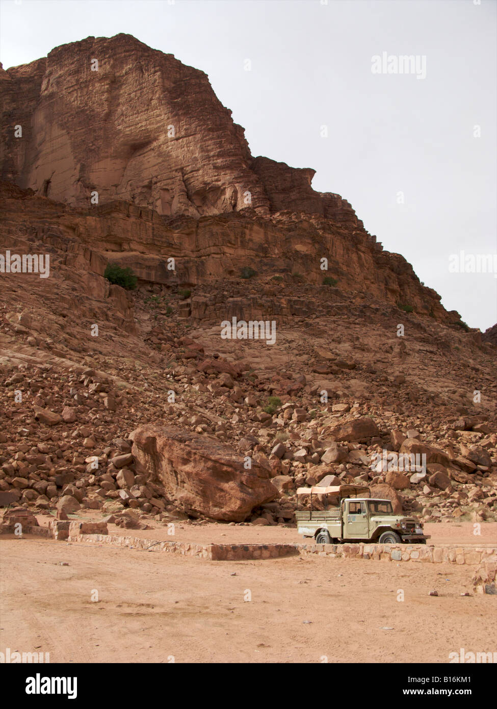 Une voiture en bas d'une falaise au milieu de la Wadi Rum, Jordanie Banque D'Images