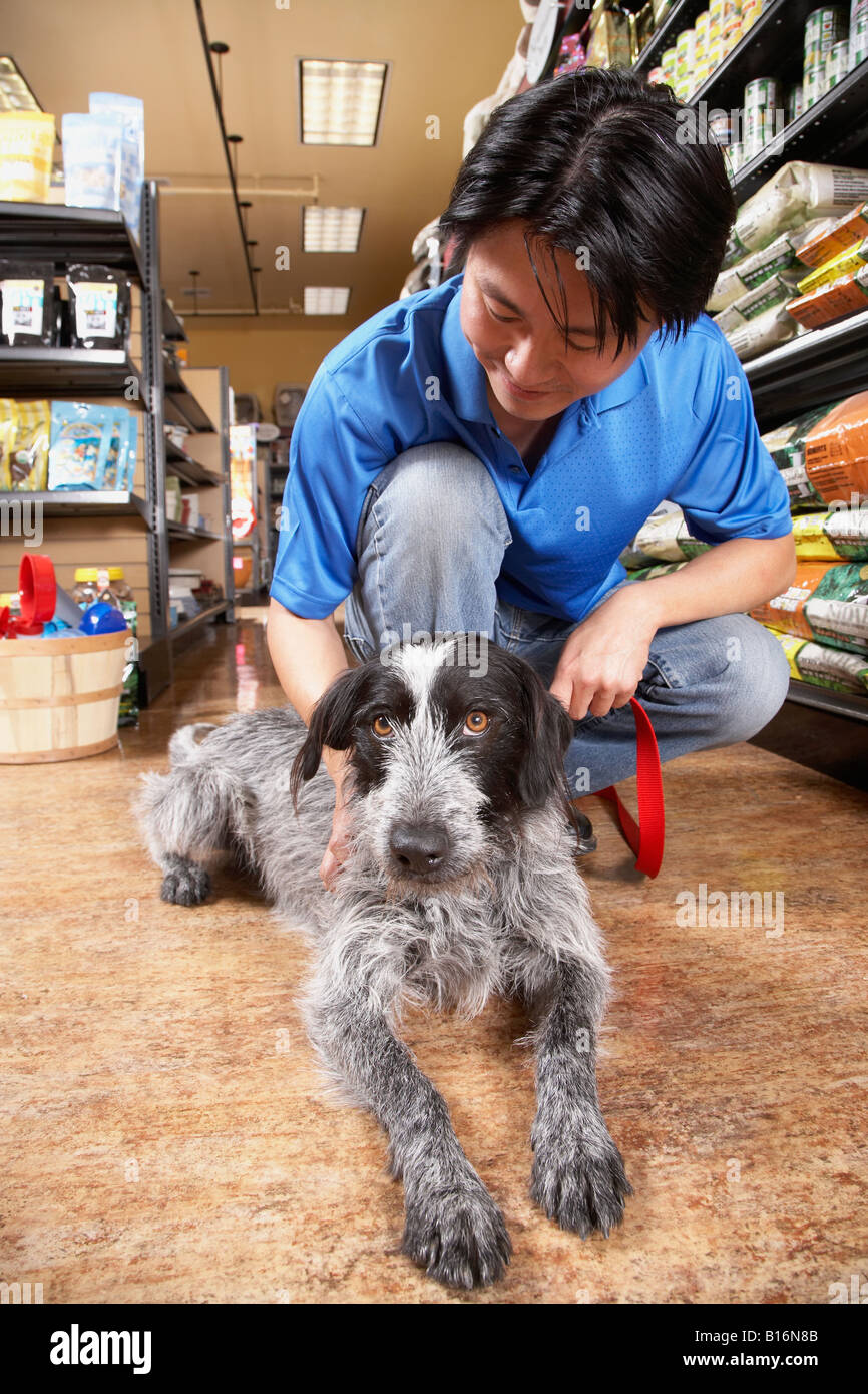 Asian man petting dog in pet store Banque D'Images