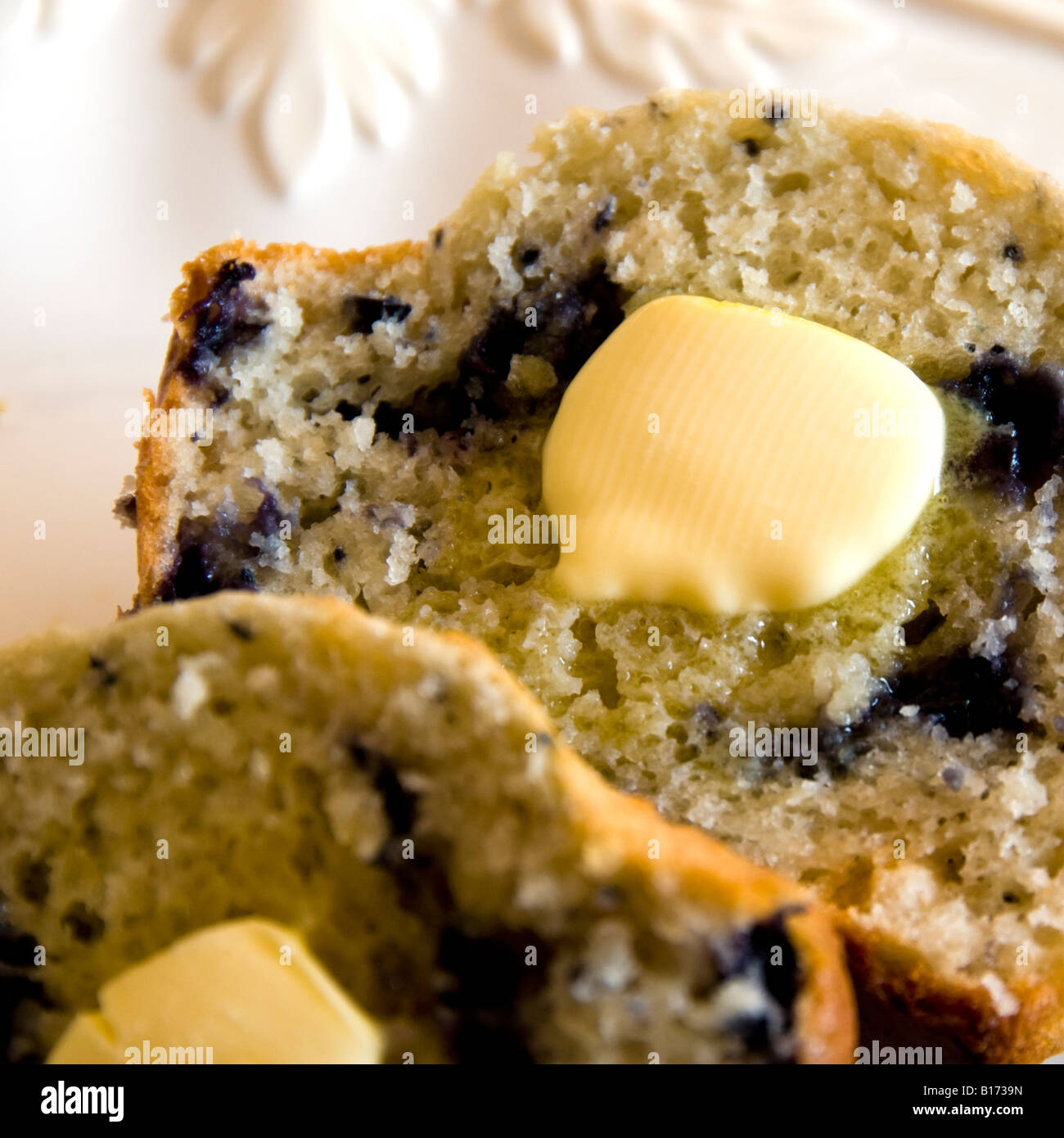 Un muffin aux bleuets, chaud du four, les couper en deux avec du beurre fondant sur chaque pièce. Banque D'Images