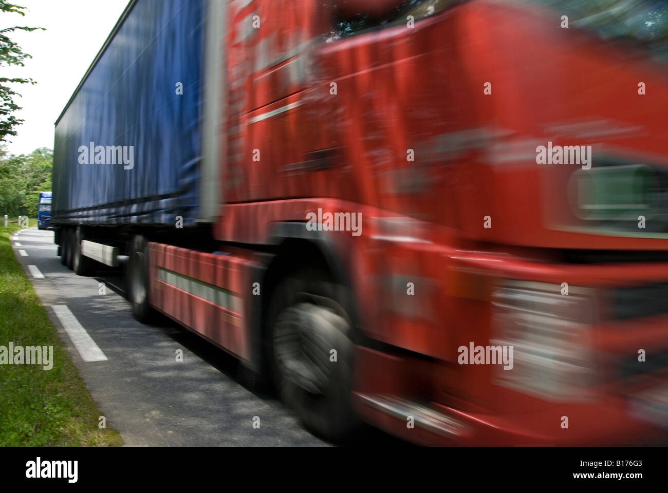 Stock photo d'un camion voyageant le long d'une route française Le camion est floue pour renforcer l'impression de vitesse Banque D'Images