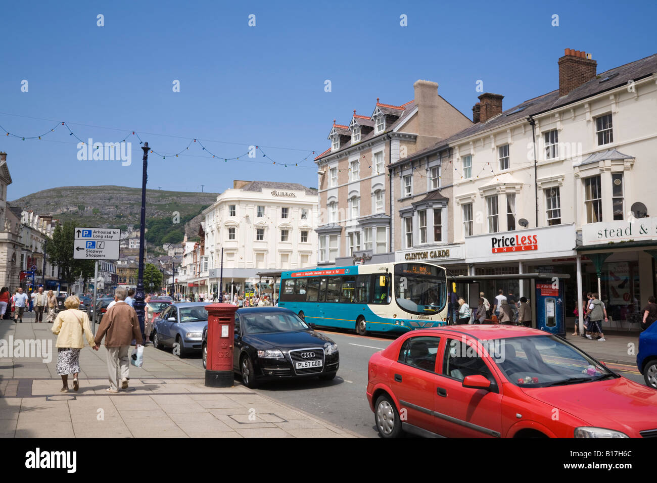 Le trafic et les piétons dans la rue animée avec des magasins en bâtiments victoriens en centre-ville. Llandudno North Wales UK Banque D'Images