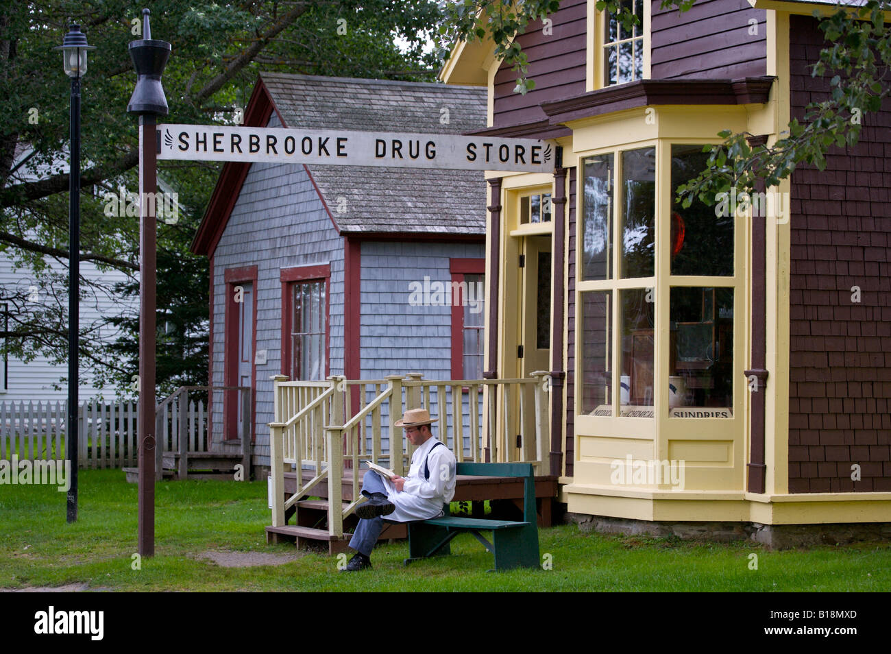 En costume d'un homme est assis à l'extérieur de la Sherbrooke Drug Store le long de la route principale, Wharf Road, dans le village de Sherbrooke Musée (un resto Banque D'Images