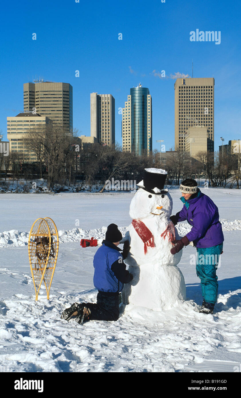 Faire un bonhomme de neige le long de la rivière Rouge avec en arrière-plan, Winnipeg, Manitoba, Canada Banque D'Images