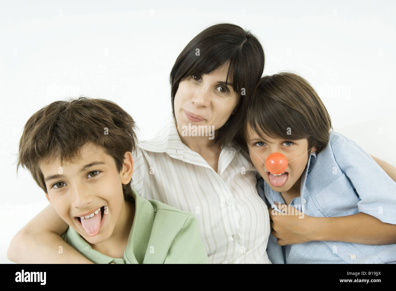 La mère et les deux fils, les garçons sortent leurs langues, l'un portant des nez de clown Banque D'Images