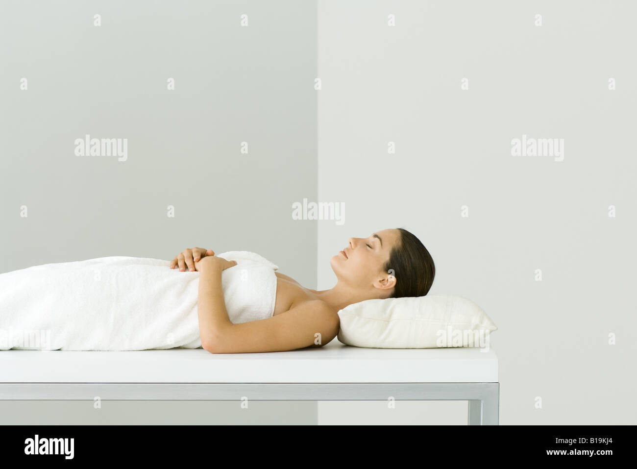 Woman lying on massage table, les yeux fermés Banque D'Images