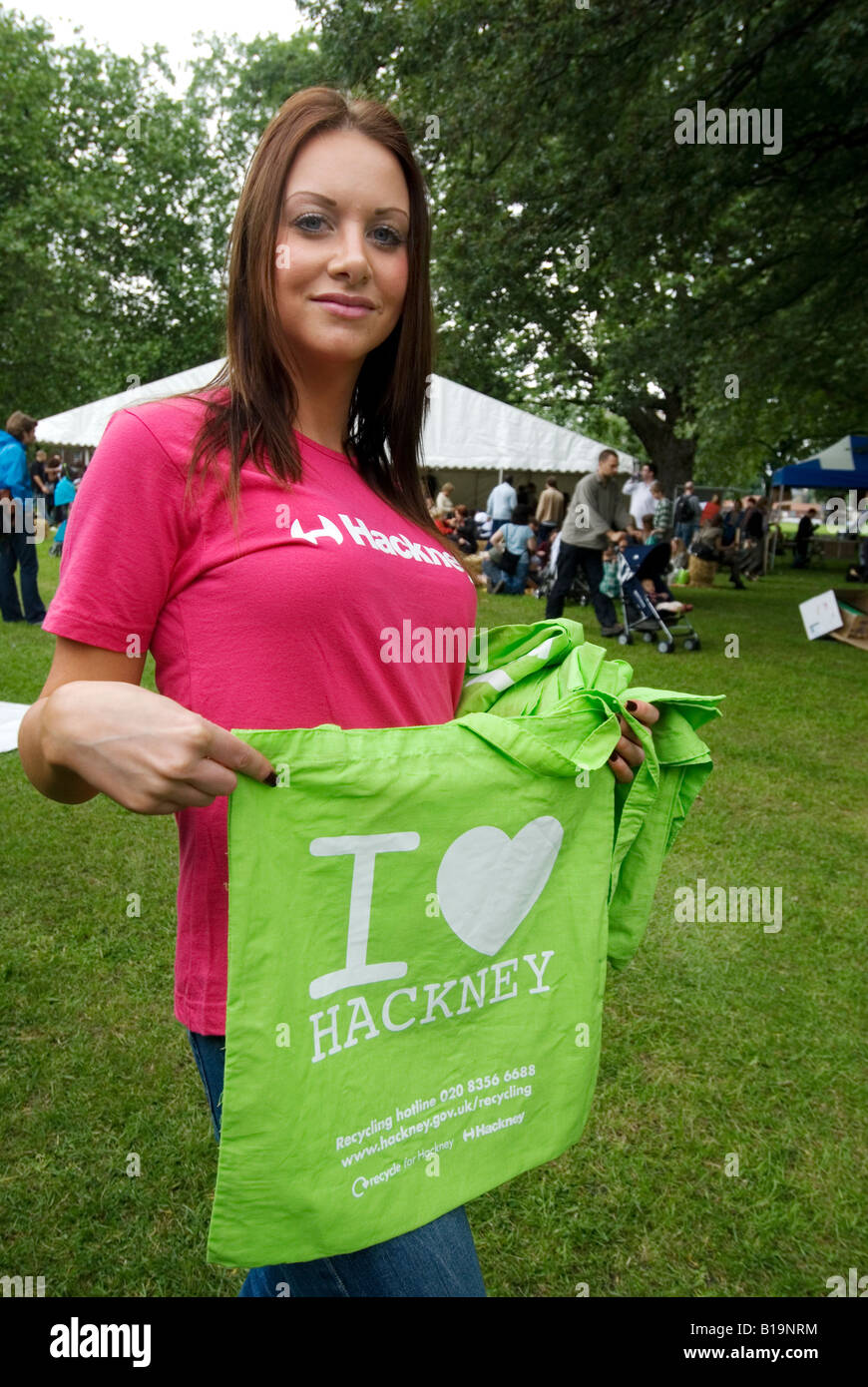 Jeune femme loin de donner des sacs en tissu réutilisables re vert avec I Love Hackney sur eux Banque D'Images