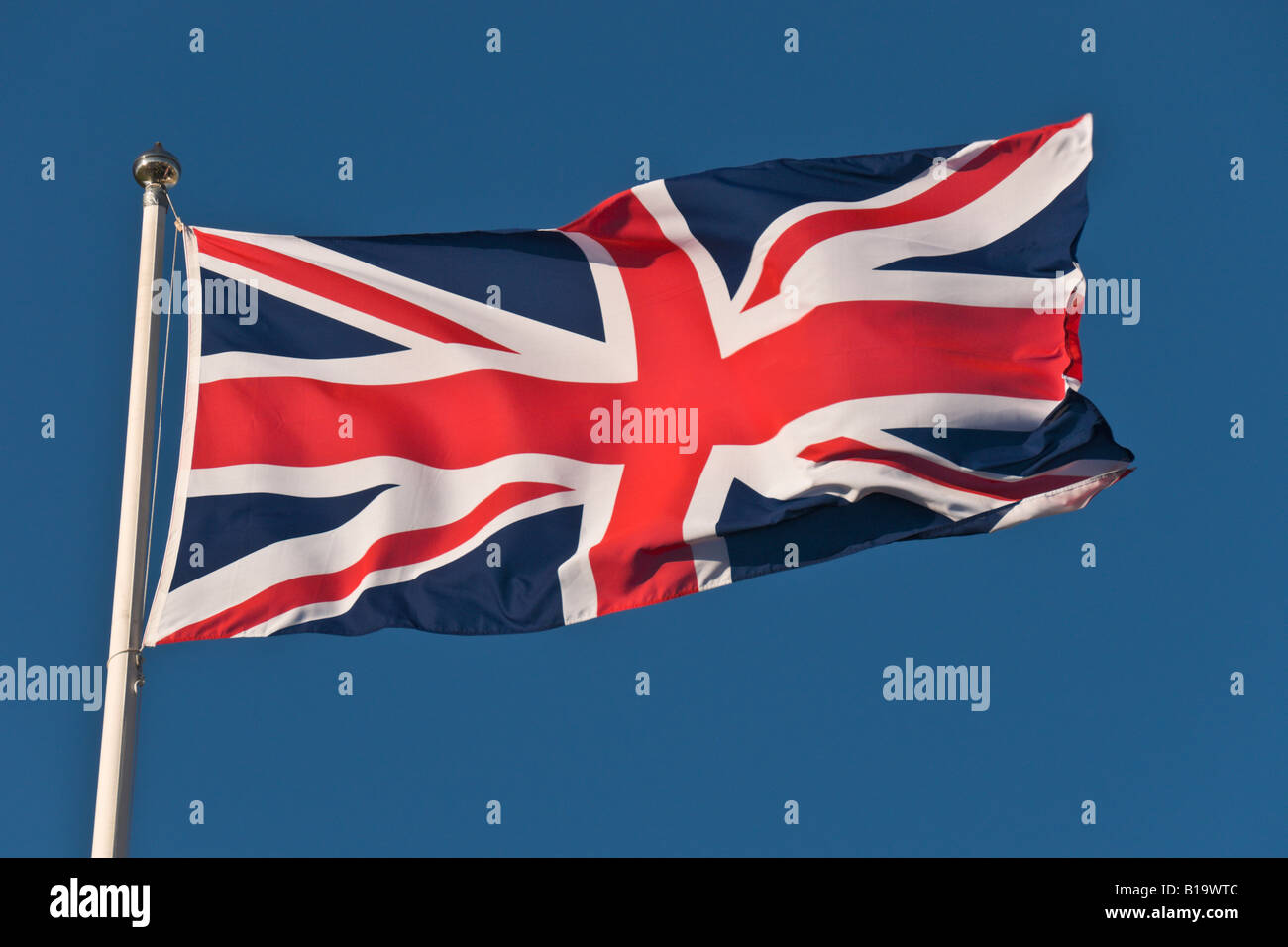 Une Union Jack ou le drapeau de Grande-Bretagne dans le vent sur un fond de ciel bleu. Banque D'Images