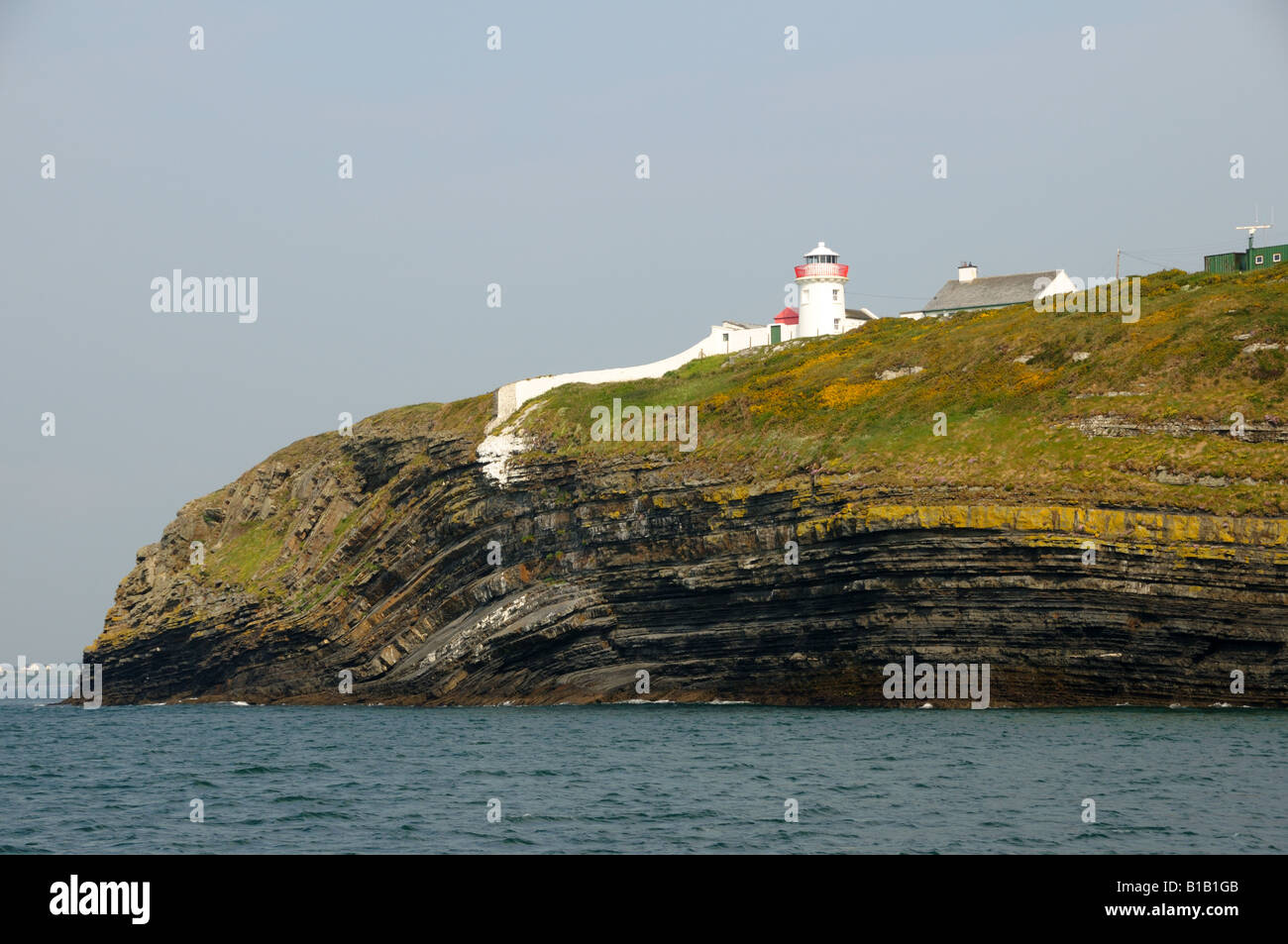 Un phare se dresse sur le rocher de la côte irlandaise. Banque D'Images