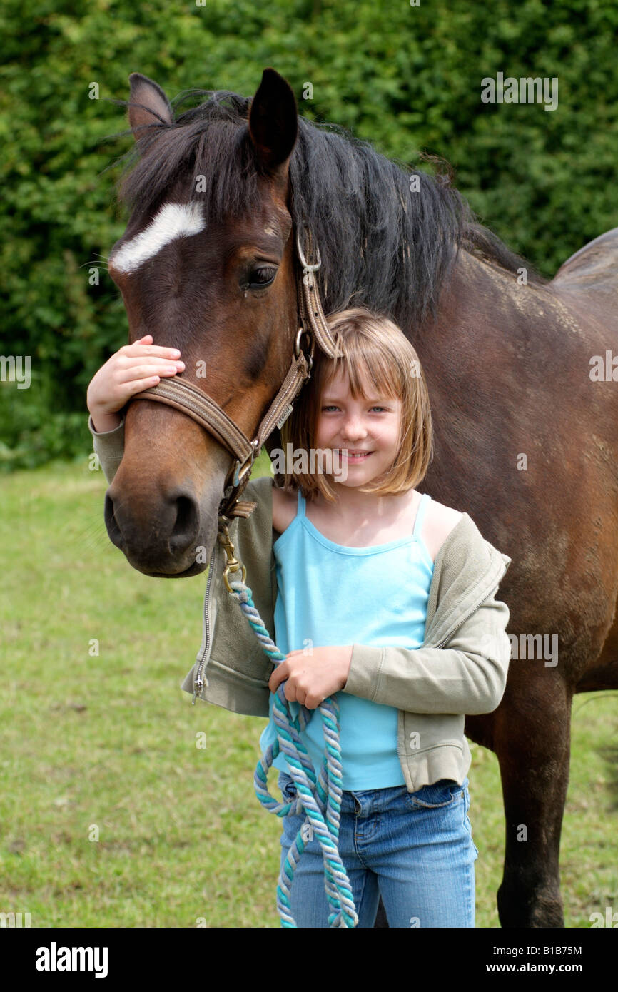 Little girl holding sa pony par le rein dans le paddock Banque D'Images