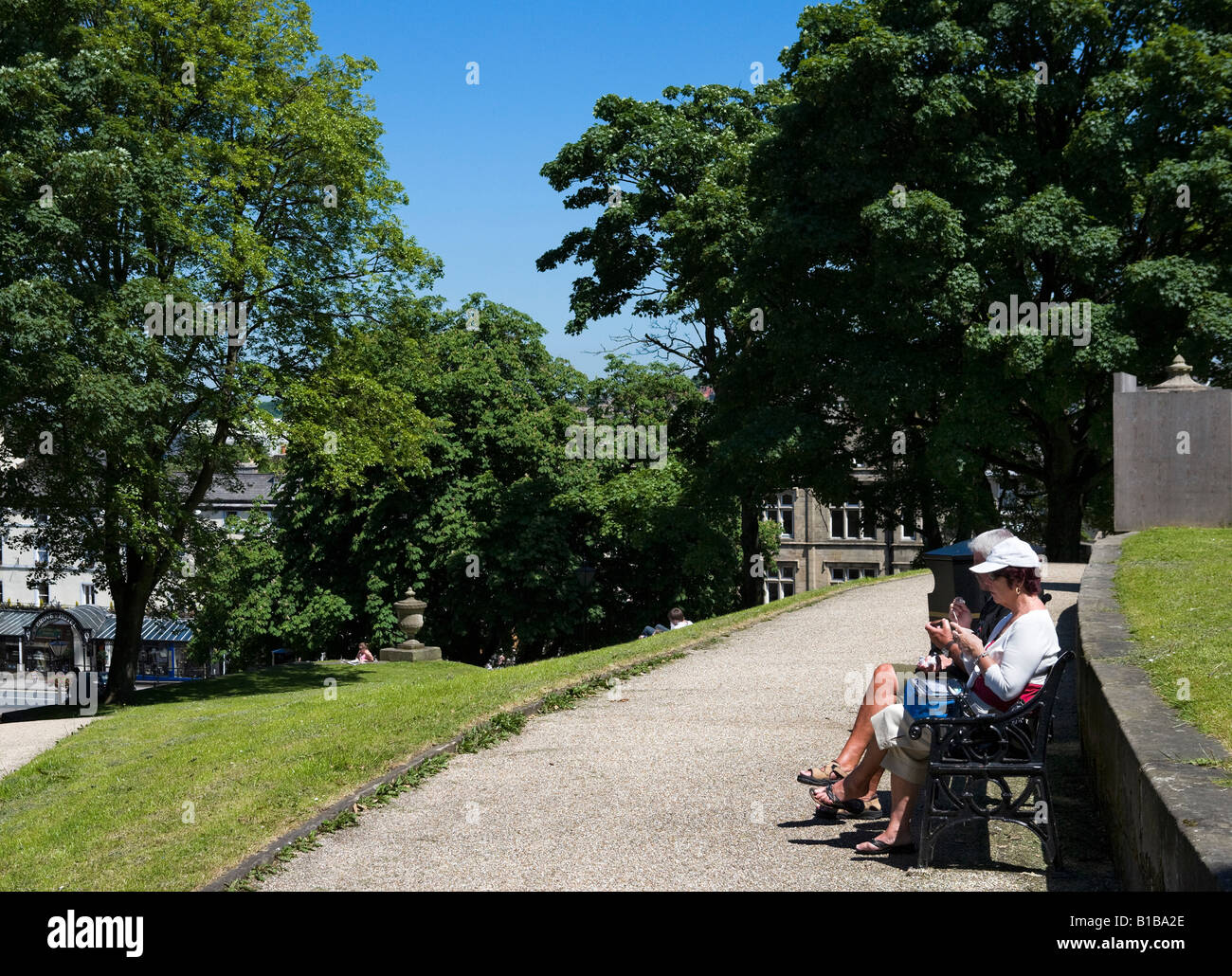 Couple eating le déjeuner sur un banc de parc, des pentes, Buxton, Peak District, Derbyshire, Angleterre Banque D'Images