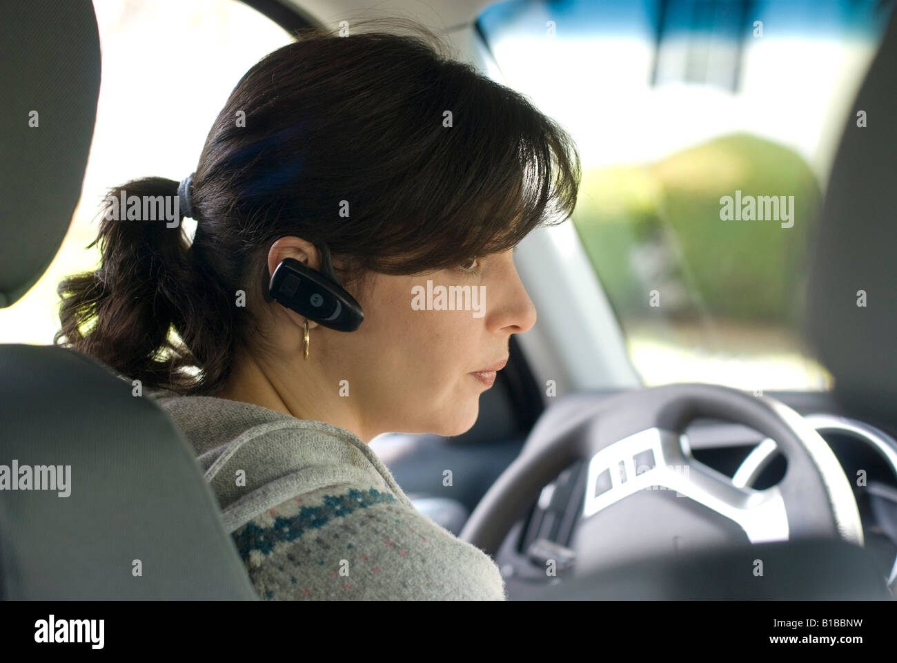 Young hispanic woman tente de pousser et de sauvegarder son nouveau SUV (véhicules utilitaires sport) tout en parlant sur son téléphone portable Banque D'Images